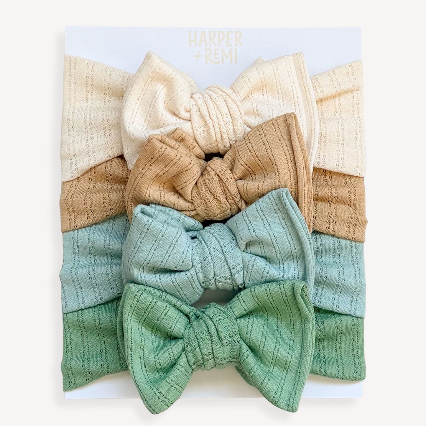 Set of colorful baby headbands in a display box held by a hand on a wooden surface.
