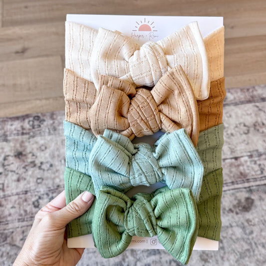 Set of colorful baby headbands in a display box held by a hand on a wooden surface.