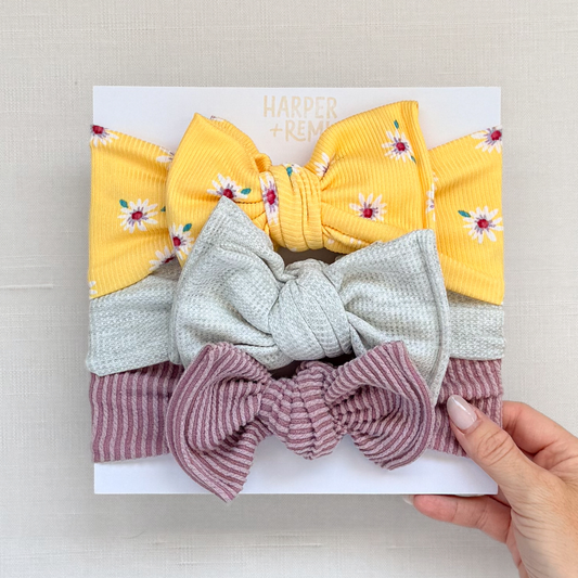 Set of colorful hair bows held by a hand against a light background