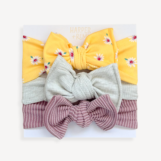 Set of colorful hair bows held by a hand against a light background