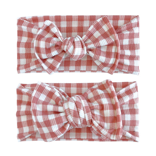 Baby girl headbands in top knot and oversized bow styles in dusty pink and white small gingham print, made from ribbed knit fabric
