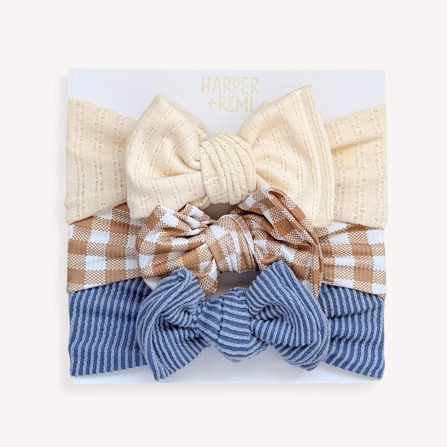 Set of ribbed hair bows on a white card held by a person wearing a brown sweater.