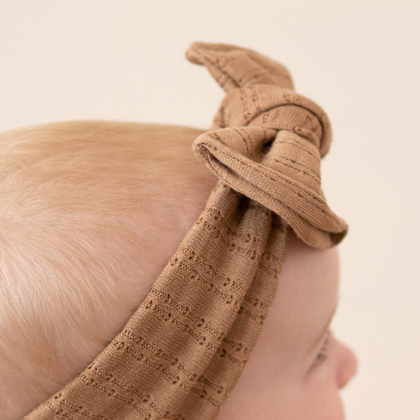 Mocha brown pointelle fabric baby headband close up texture.