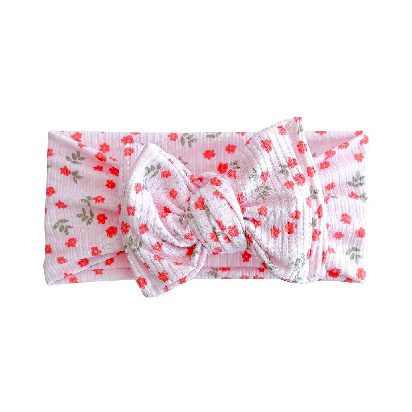 Oversized bow baby headband in light pink with dainty coral floral pattern, crafted from ribbed knit fabric, displayed on a white background