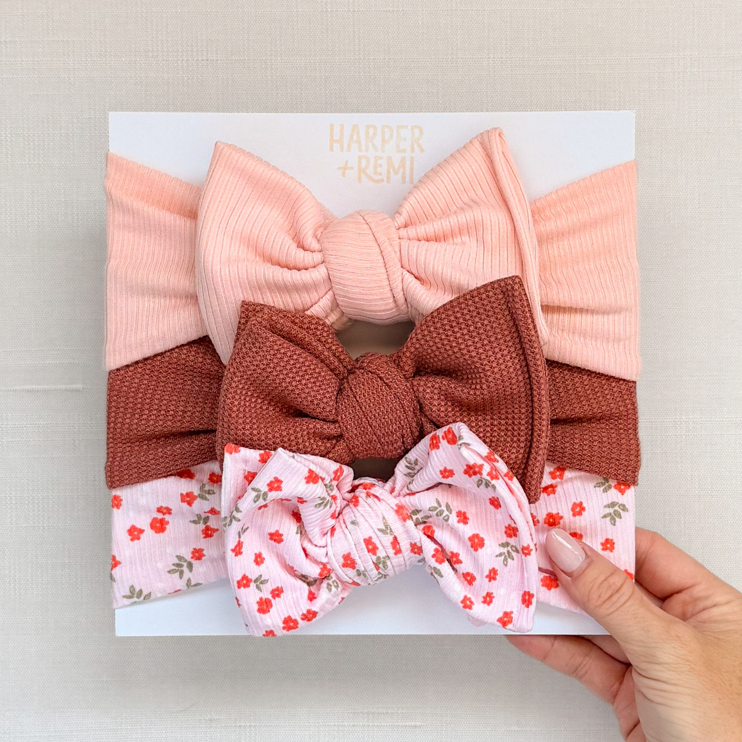 Set of oversized baby bows hand held on a branded card.