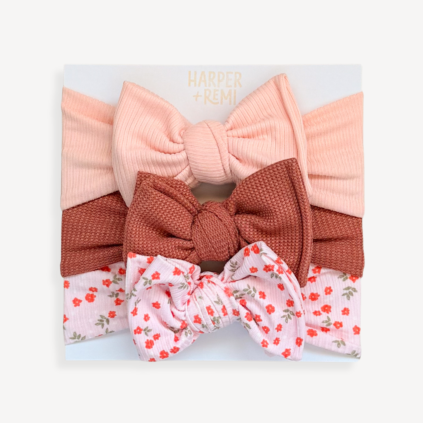 Set of oversized baby bows hand held on a branded card.