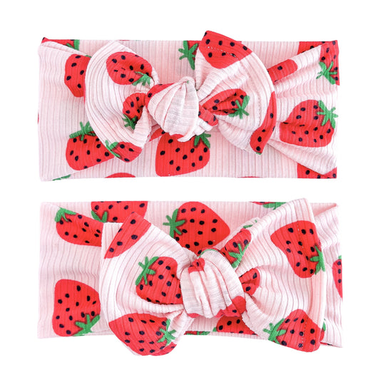 Baby girl headbands in top knot and oversized bow styles in light pink with red strawberry pattern, made from ribbed knit fabric
