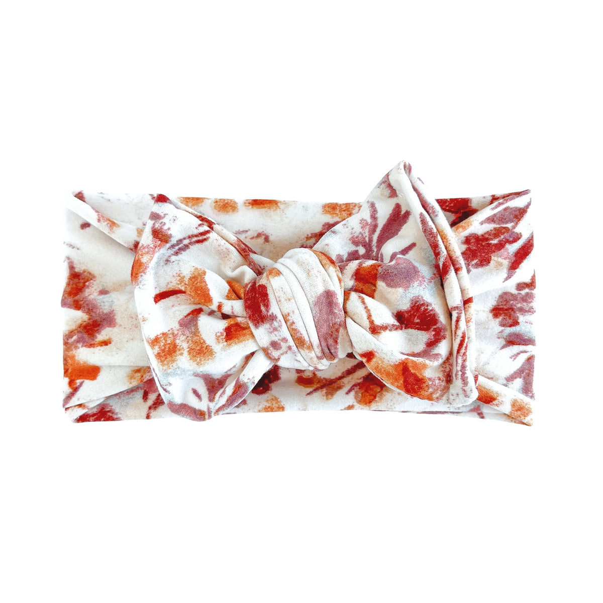 Oversized bow baby headband in white with watercolor rust and spice floral print, crafted from double brushed knit fabric, displayed on a white background