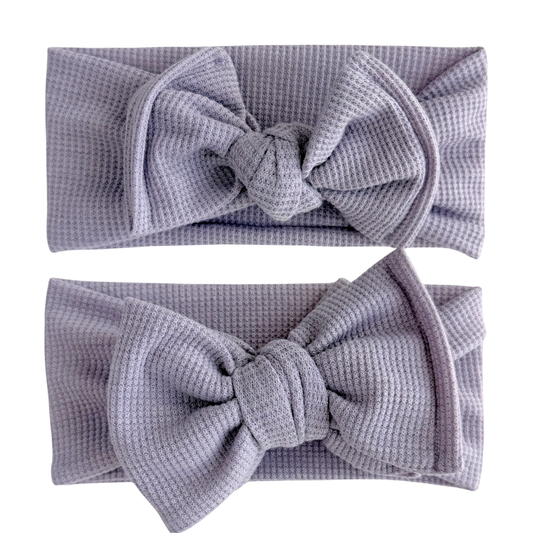 Two lavender textured headbands on a white background. Top is a top knot, bottom is an oversized bow.