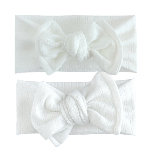 Baby girl headbands in top knot and oversized bow styles in white, made from pointelle knit fabric