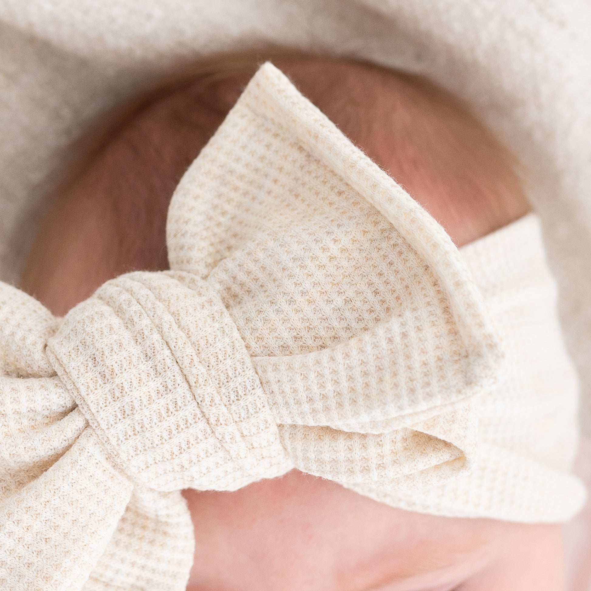 Close-up of a waffle textured beige bow headband on a blurred background