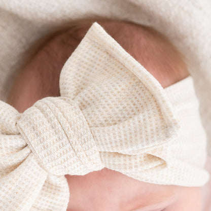 Close-up of a waffle textured beige bow headband on a blurred background