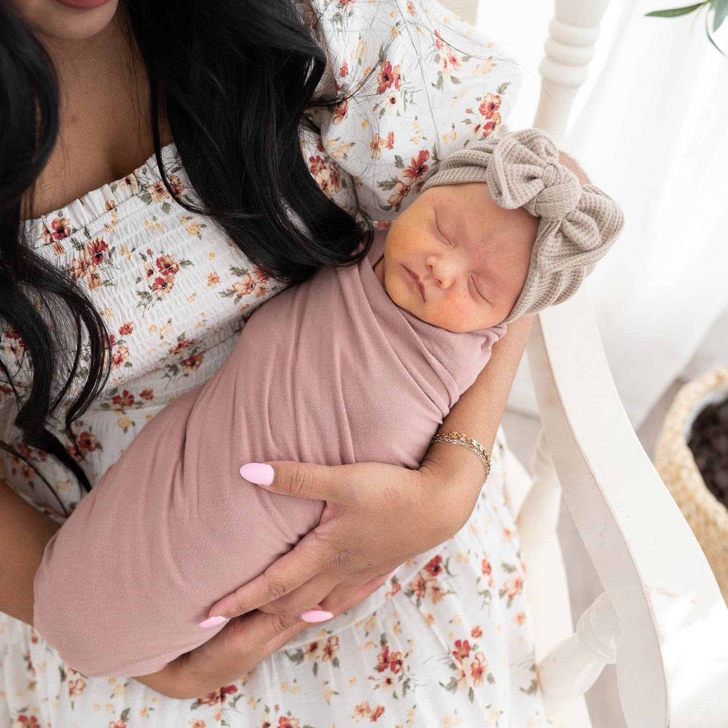 Woman holding a swaddled baby wearing a taupe waffle headband in a soft, indoor setting.