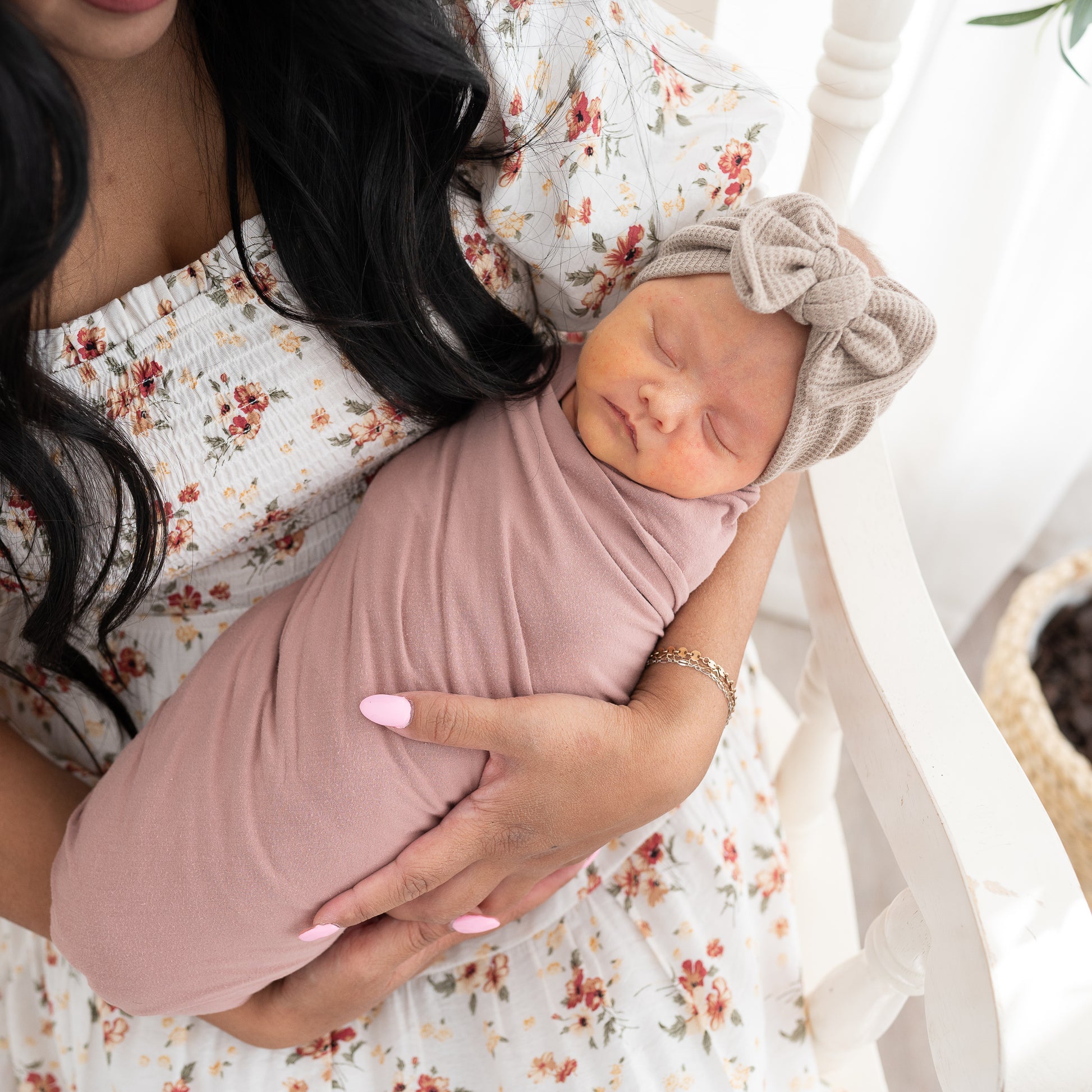 Woman holding a swaddled baby wearing a taupe waffle headband in a soft, indoor setting.