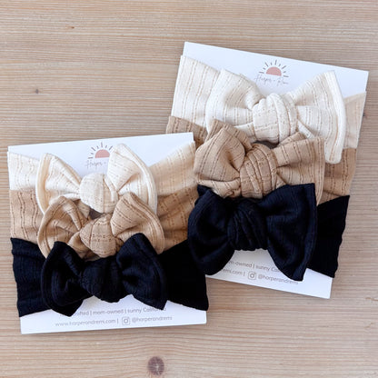Set of three hair bows on branded card packaging on a wooden surface