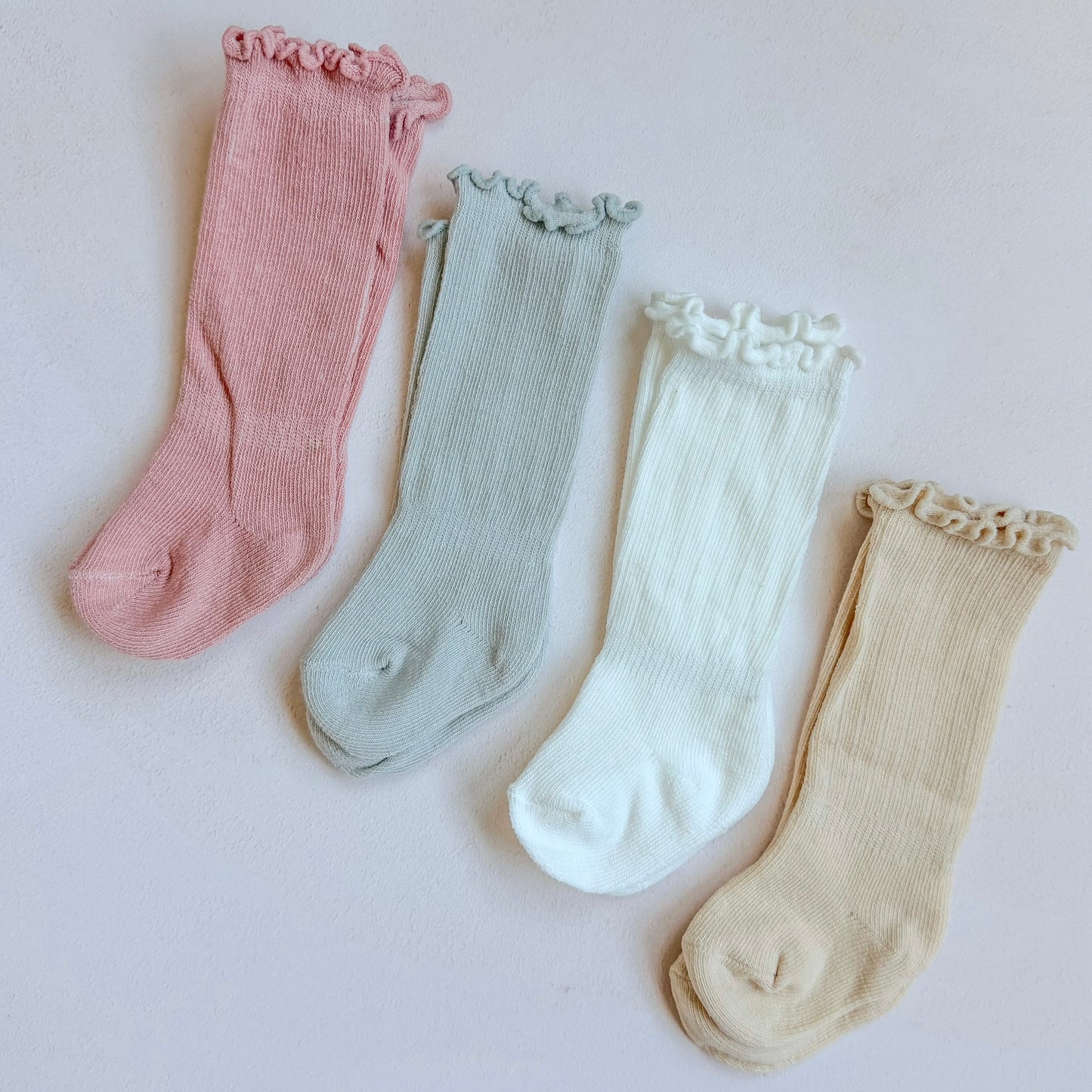 Four pairs of colorful socks with ruffled top on a light background