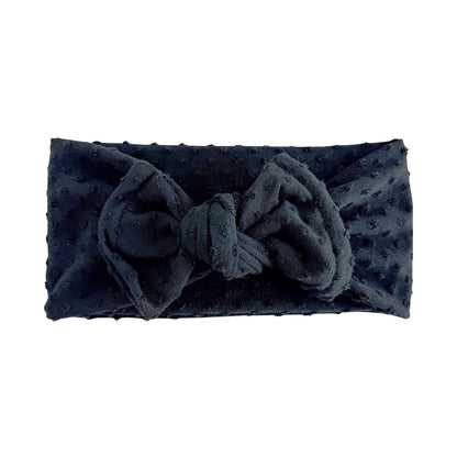 Black Swiss dots headband with a large top knot bow on a white background