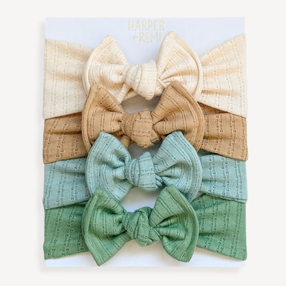 Set of fabric bows on a card held by a hand with a wooden surface background