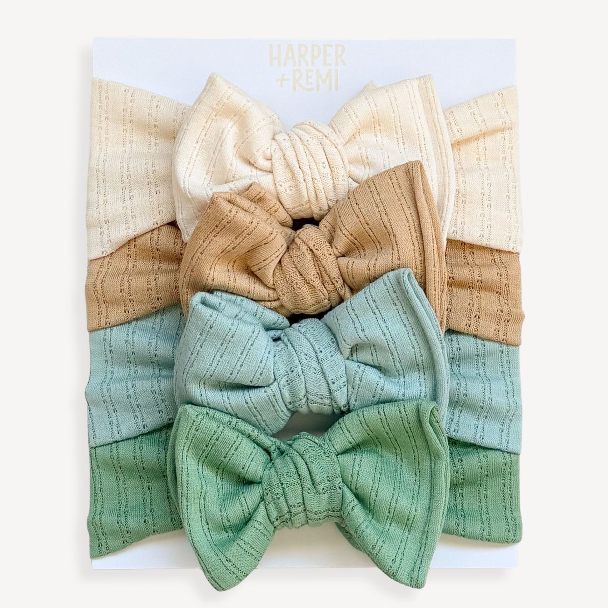 Set of colorful baby headbands in a display box held by a hand on a wooden surface.