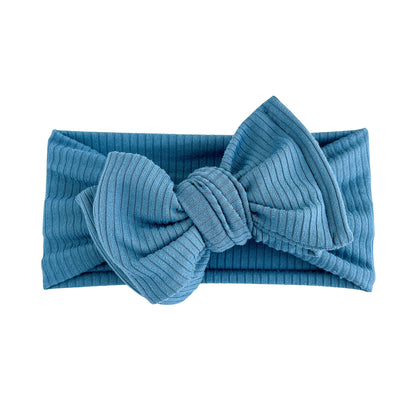 Oversized bow baby headband in blue, crafted from ribbed knit fabric, displayed on a white background