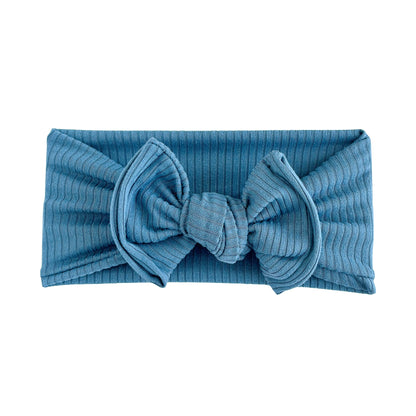 Blue ribbed headband with a top knot bow on a white background