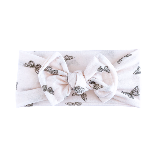 Blush top knot headband with butterfly pattern on a white background