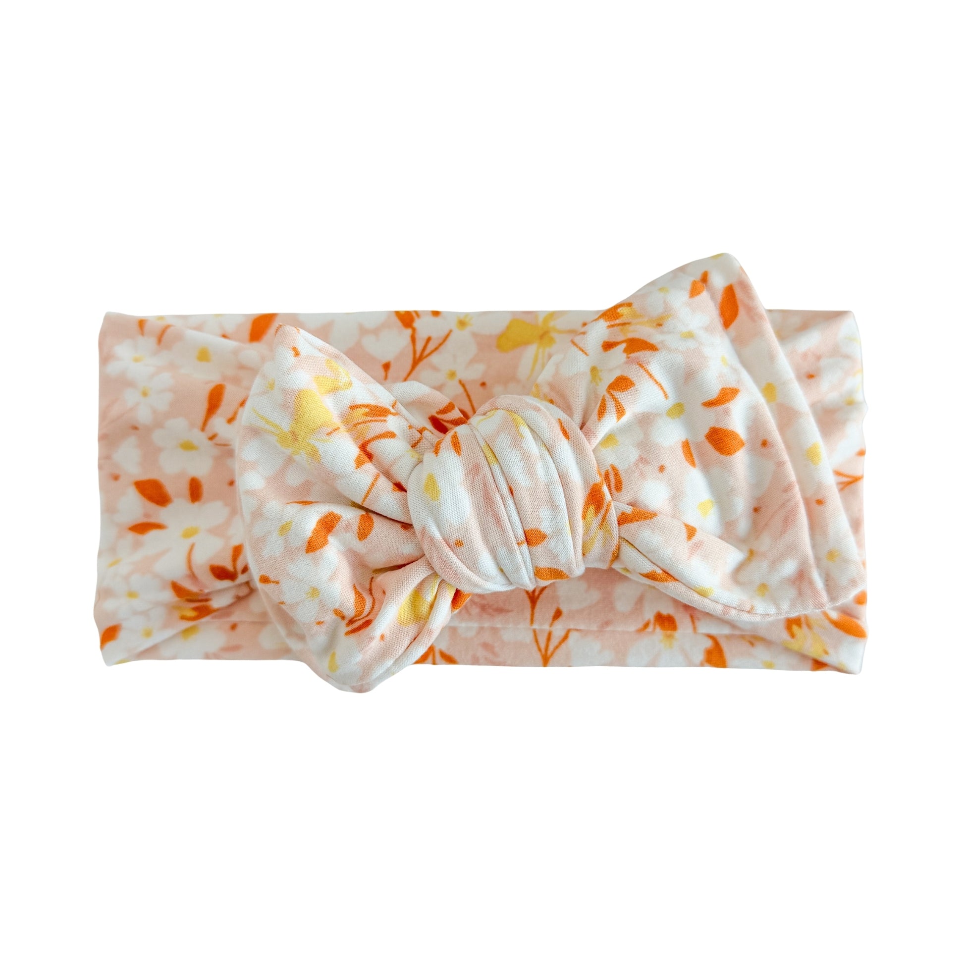 Oversized bow baby headband in light blush (nude pink) with white and coral floral print, crafted from double brushed knit fabric, displayed on a white background