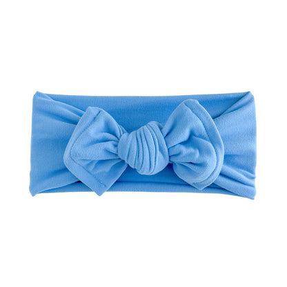 Top knot bow baby headband in bright blue, crafted from double brushed knit fabric, displayed on a white background