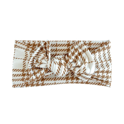 Top knot bow baby headband in cream with brown plaid print, crafted from double brushed knit fabric, displayed on a white background