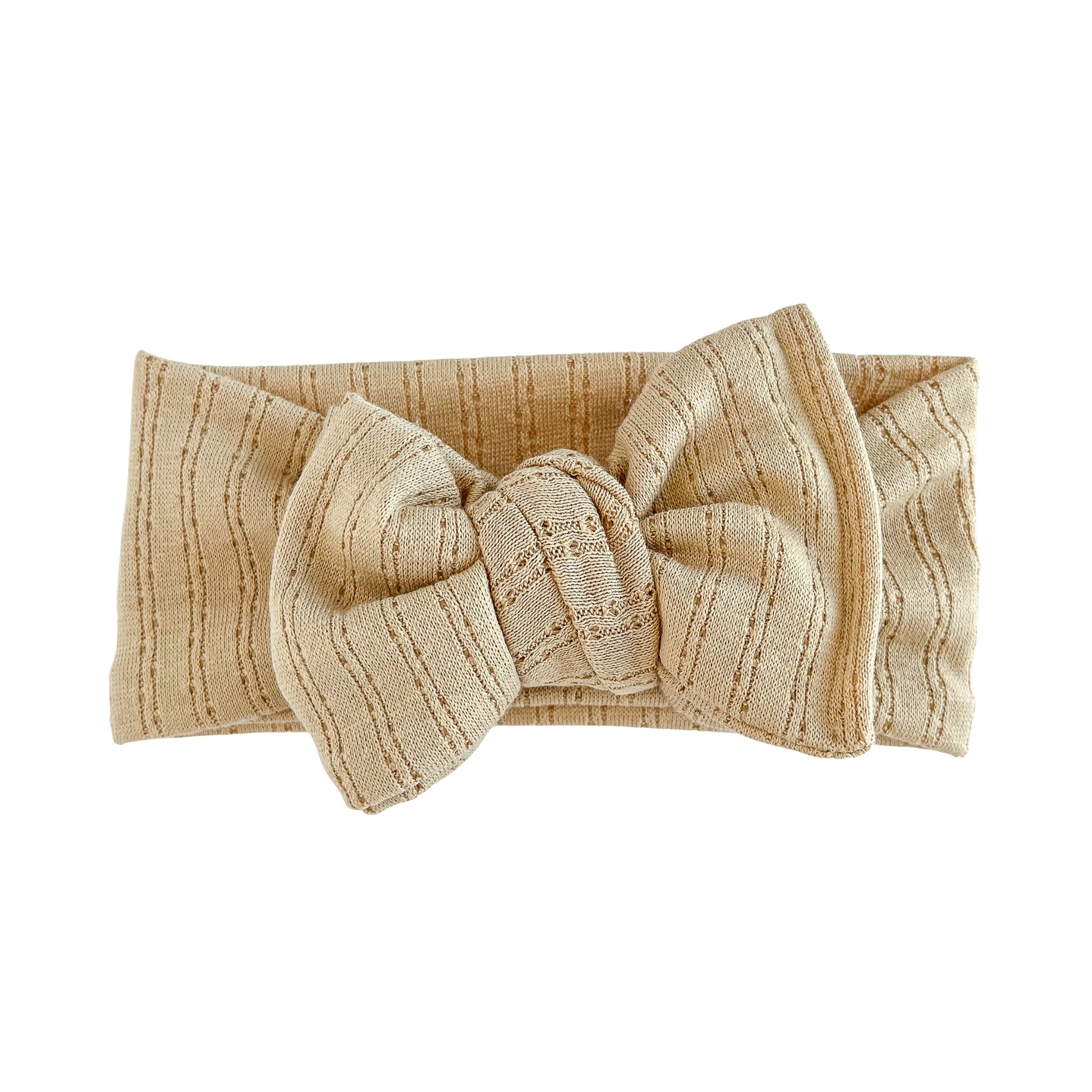 Oversized bow baby headband in caramel (light brown) crafted from pointelle knit fabric, displayed on a white background