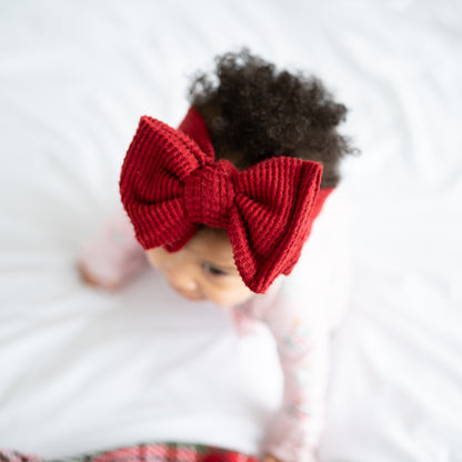 Baby doll with a large red bow on a white background