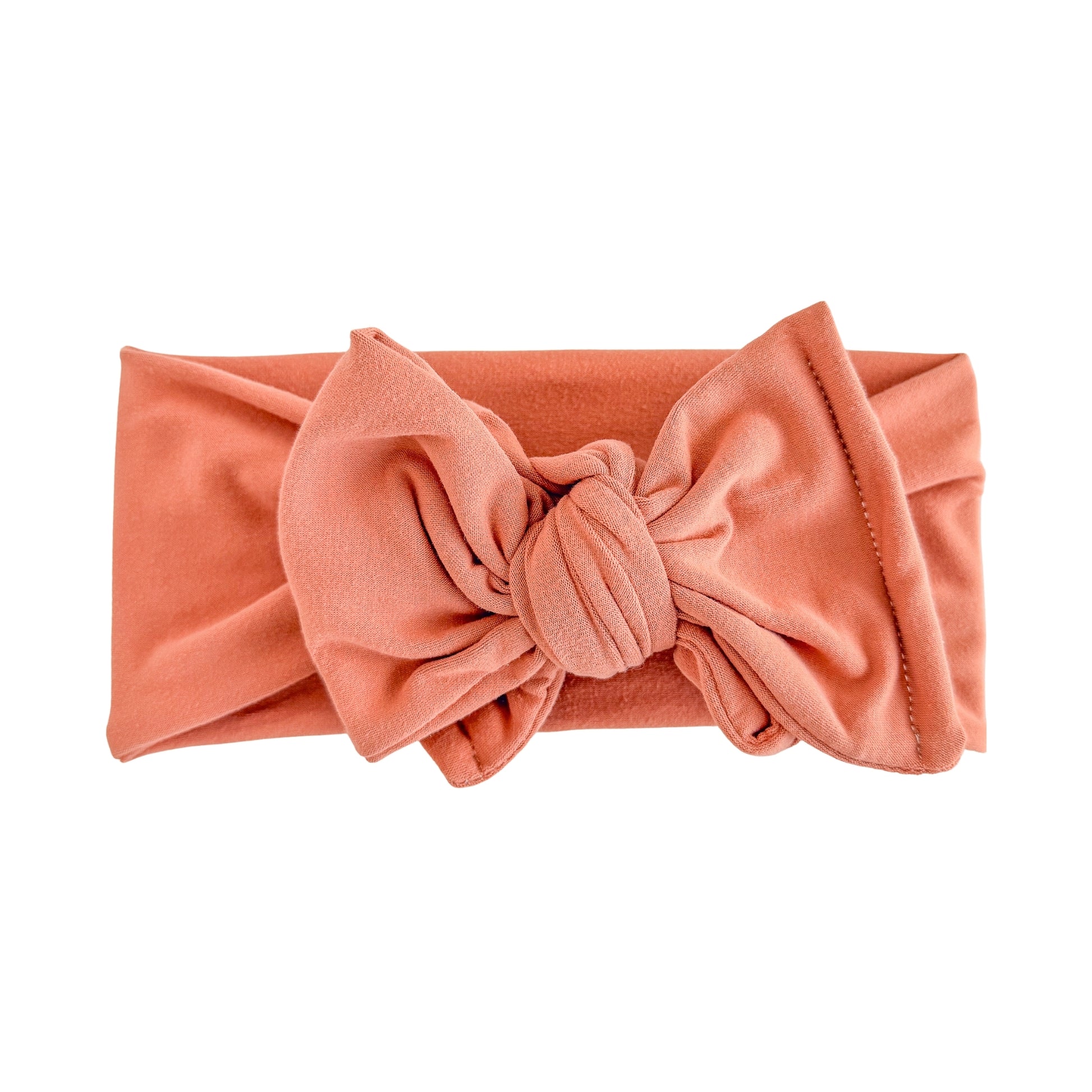 Oversized bow baby headband in coral, crafted from double brushed knit fabric, displayed on a white background