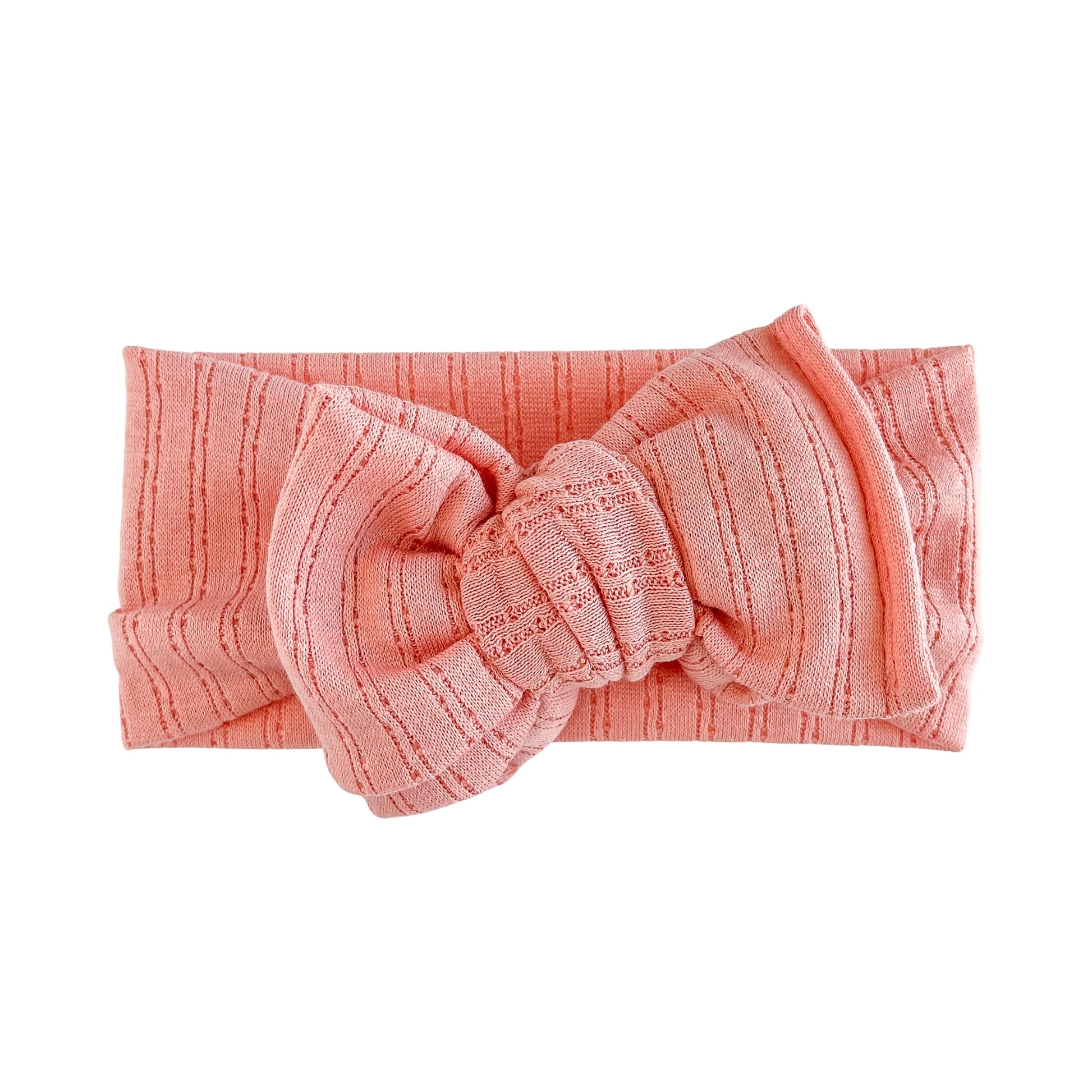 Oversized bow baby headband in coral crafted from pointelle knit fabric, displayed on a white background