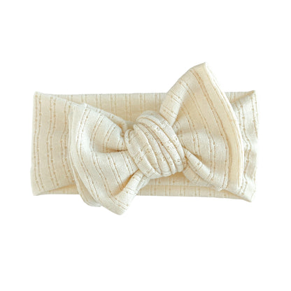 Oversized bow baby headband in cream (warm beige) crafted from pointelle knit fabric, displayed on a white background