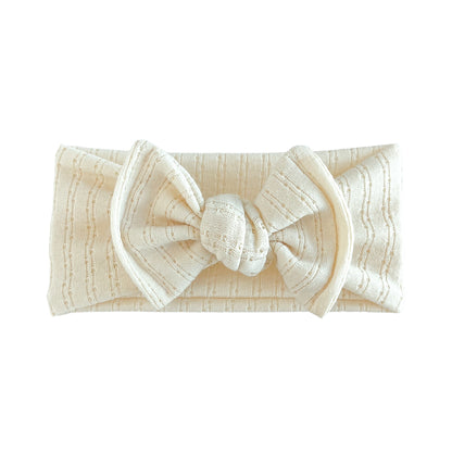 Top knot baby headband in cream, crafted from pointelle knit fabric, displayed on a white background