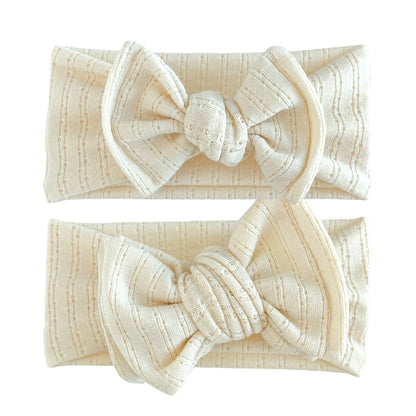 Baby girl headbands in top knot and oversized bow styles in cream, made from pointelle knit fabric