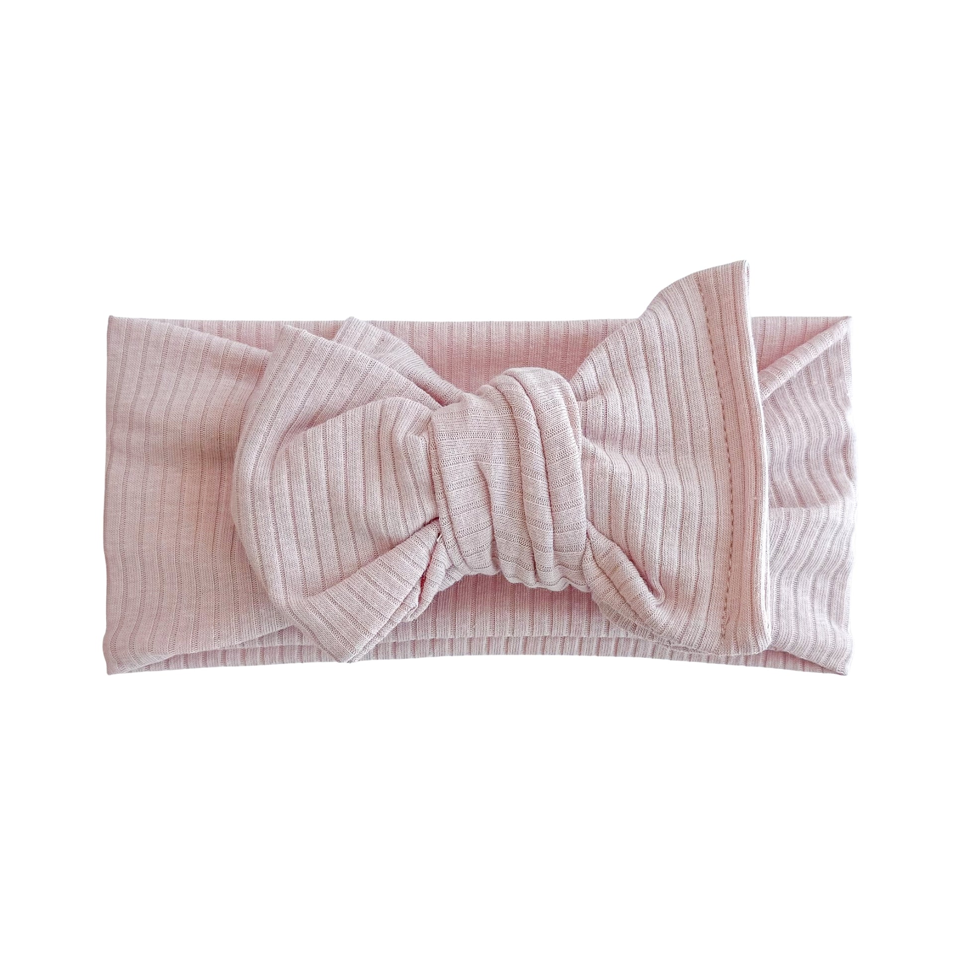 Oversized bow baby headband in dusty pink, crafted from ribbed cotton jersey knit fabric, displayed on a white background