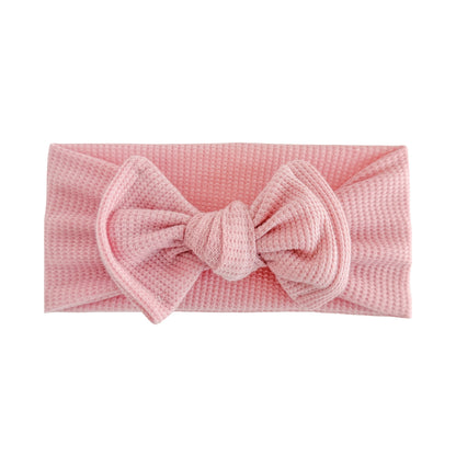 Top knot baby headband in dusty pink, crafted from waffle knit fabric, displayed on a white background