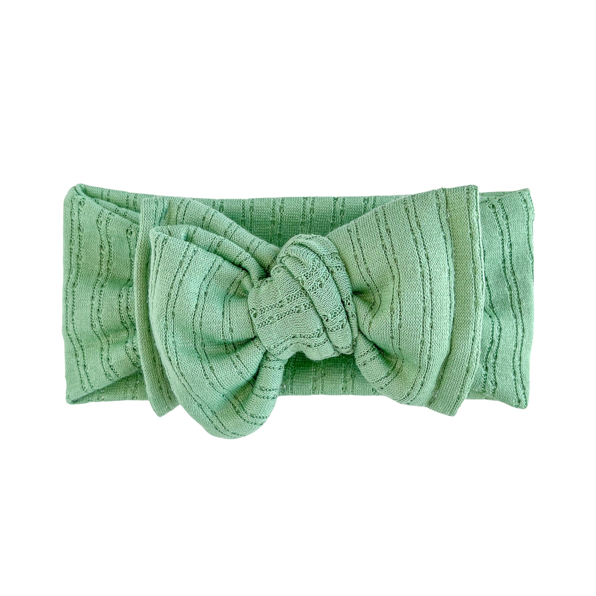 Oversized bow baby headband in green apple crafted from pointelle knit fabric, displayed on a white background