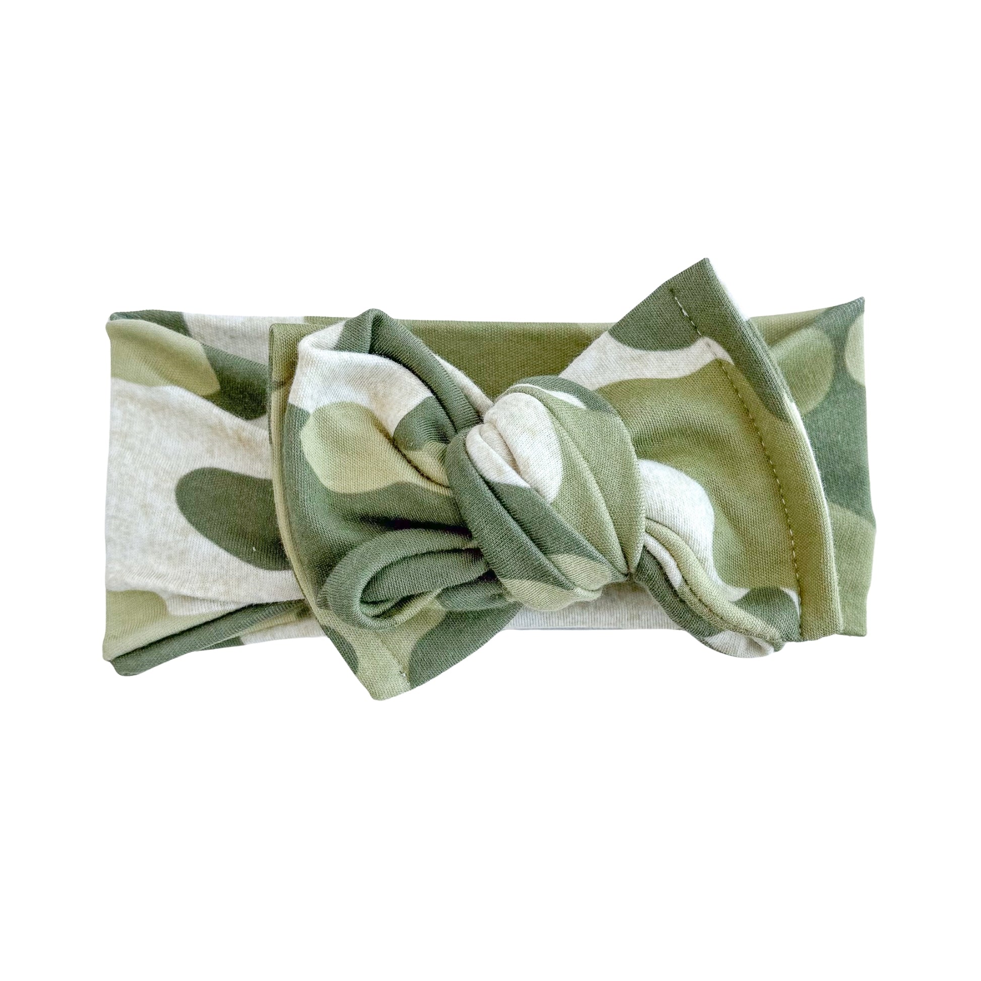 Oversized bow baby headband in green camouflage print, crafted from cotton jersey knit fabric, displayed on a white background