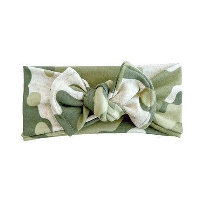 Top knot baby headband in green camo print, crafted from cotton jersey knit fabric, displayed on a white background