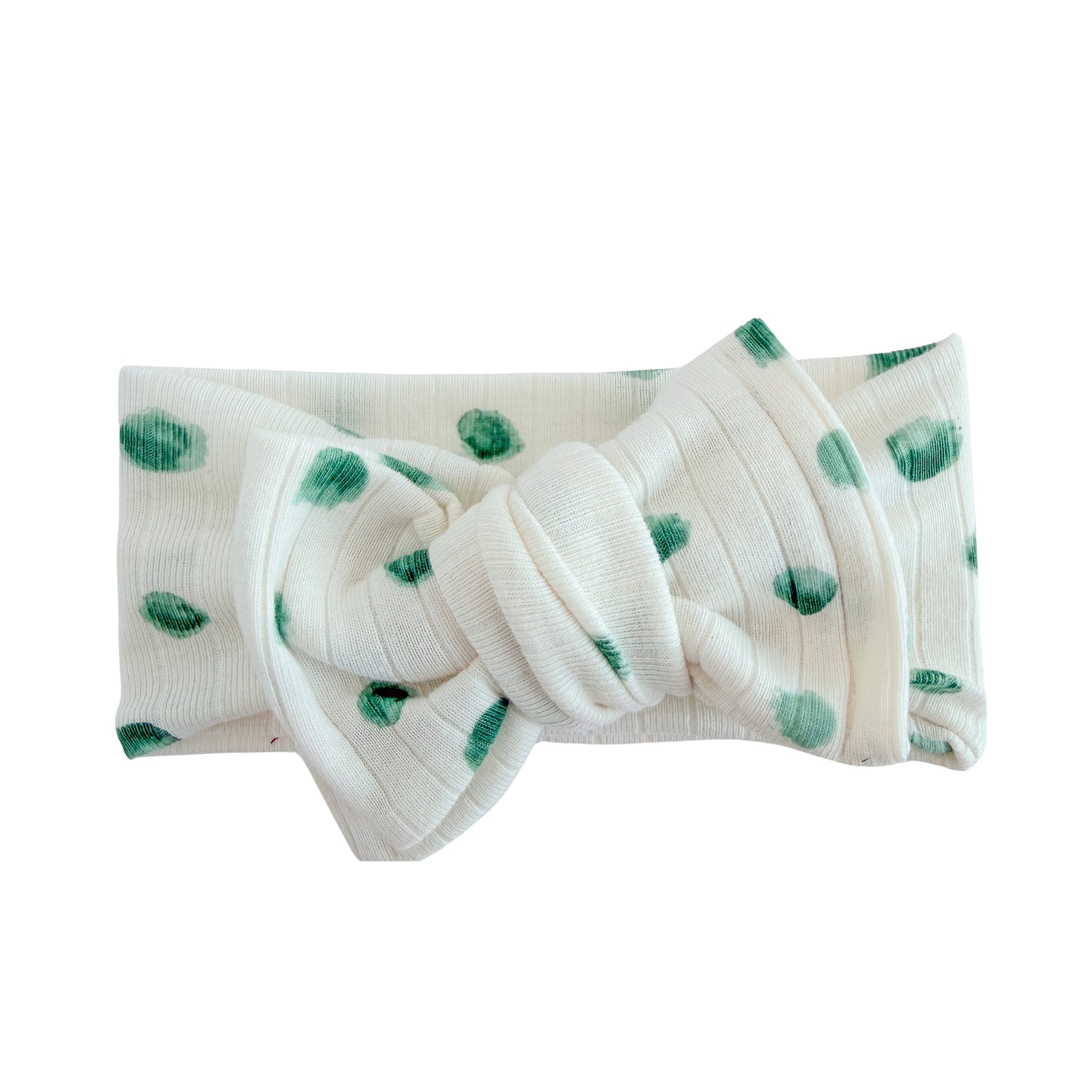 Top knot baby headband in white with watercolor green dot print, crafted from wide ribbed knit fabric, displayed on a white background
