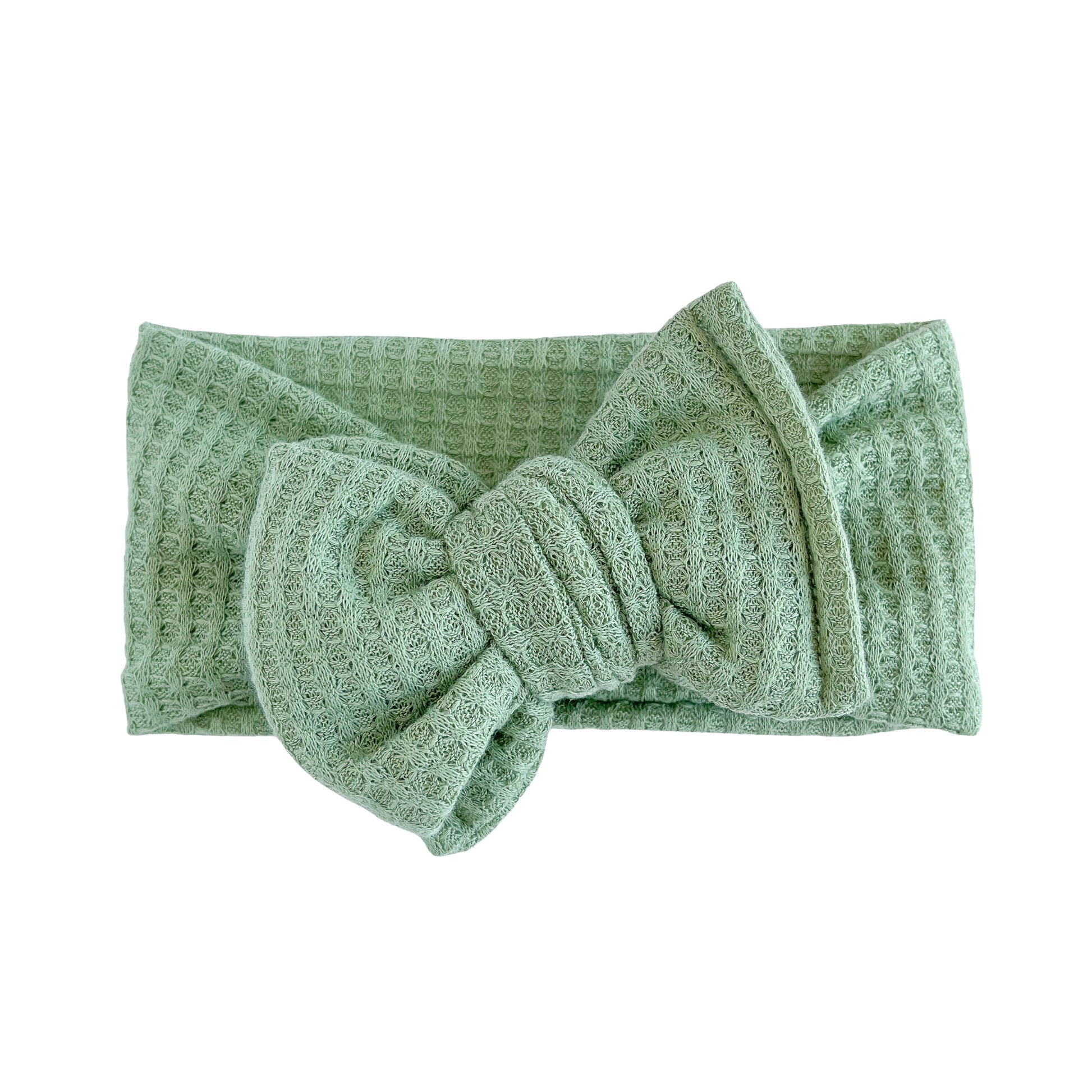 Oversized bow baby headband in green, crafted from honeycomb waffle knit fabric, displayed on a white background