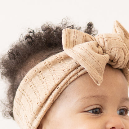 Caramel brown pointelle fabric baby headband close up texture.