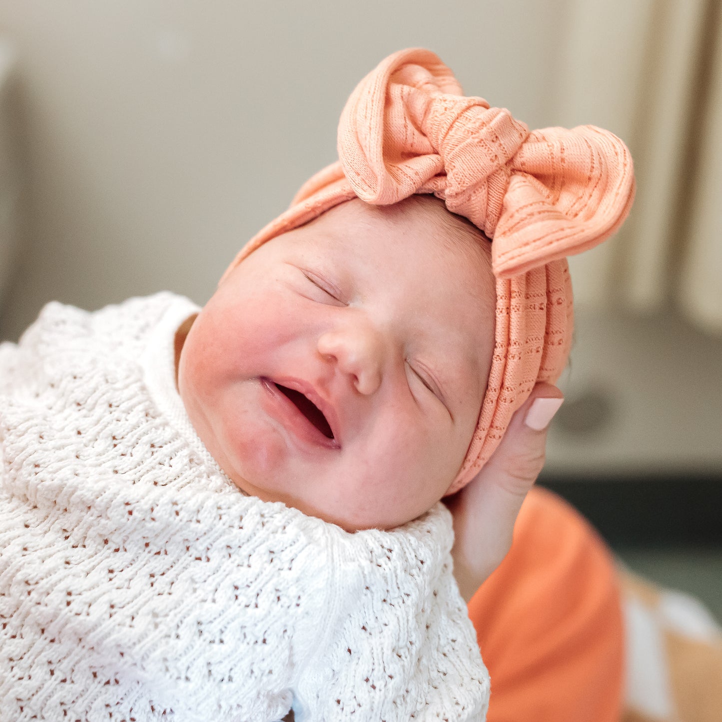 Coral pointelle fabric baby headband close up texture, shown on newborn baby girl.