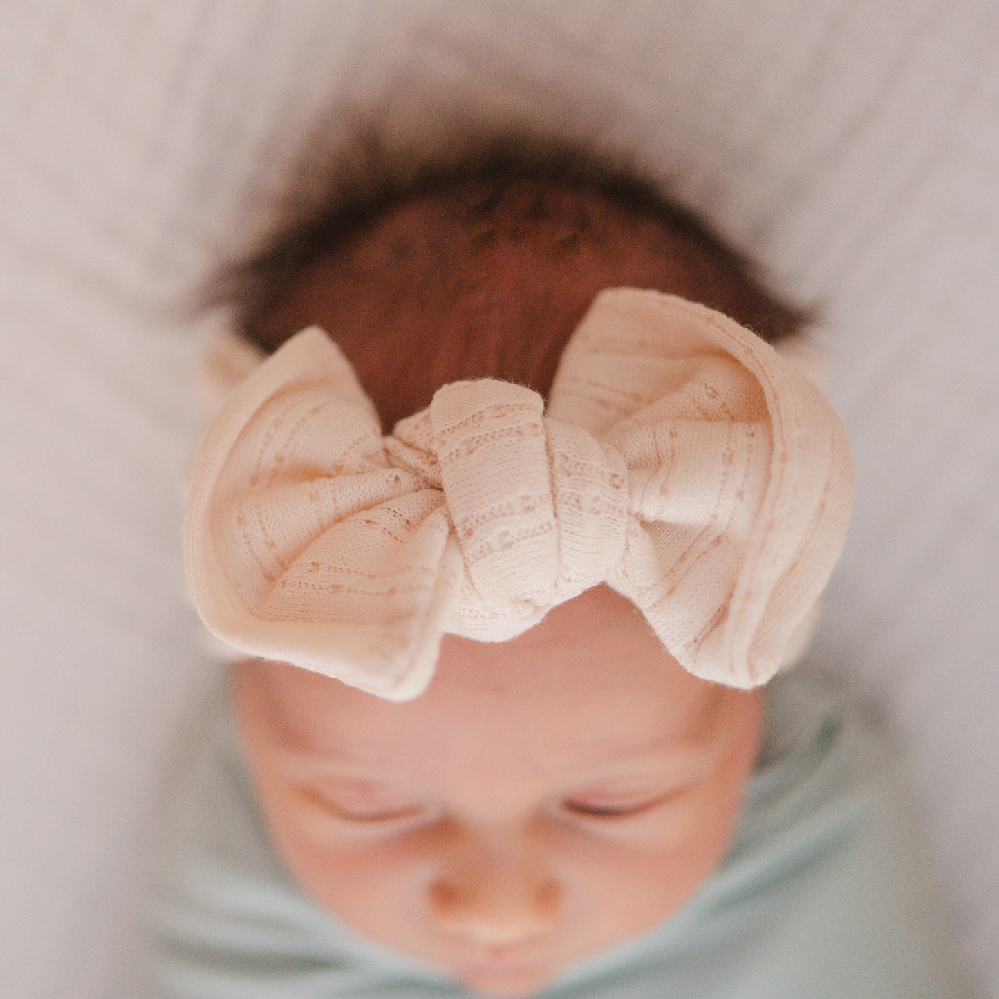 Cream pointelle fabric baby headband close up texture.