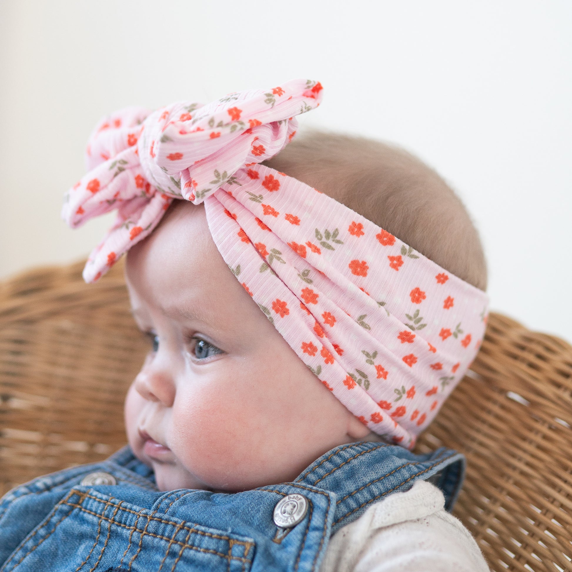 Side view of baby wearing a floral headband with a blurred background