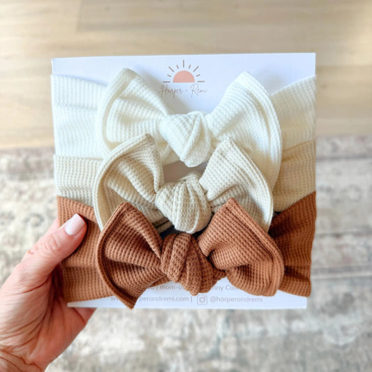 Set of white and brown waffle knit top knot headbands held against a neutral background