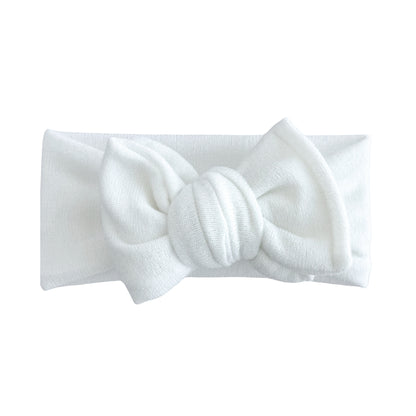 Oversized bow baby headband in ivory, crafted from stretchy terry cloth knit fabric, displayed on a white background