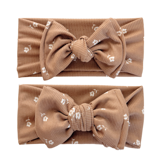 Two brown headbands with large bows and small white floral patterns on a white background